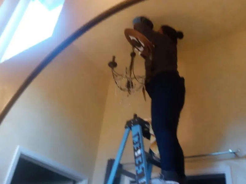 Electrician installing a chandelier in a Fayetteville residence